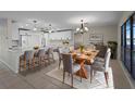 Bright, open dining and kitchen area featuring modern white cabinetry, pendant lighting, and a large wooden dining table at 318 Oakwood Cir, Englewood, FL 34223