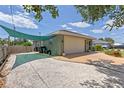 View of the side exterior highlighting the two-car garage, gravel driveway, and partial shade awning at 5264 Albion Rd, Venice, FL 34293