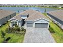 Aerial view of beautiful single-story home showcasing landscaping, paved driveway, and serene lake views at 8529 Saint Kitts Cir, Englewood, FL 34224