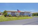 Single-story home featuring an American flag, manicured lawn, and beautiful landscaping at 8701 Pickwick Rd, North Port, FL 34287