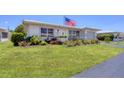 Attractive single-story home with a beautiful green lawn, American flag, and charming landscape at 8701 Pickwick Rd, North Port, FL 34287