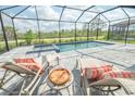 Inviting screened-in pool area with lounge chairs, a table, and a view of the lush greenery at 12548 Wellen Golf St, Venice, FL 34293