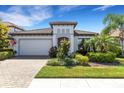 Charming single-story home featuring a tile roof, brick driveway, and lush tropical landscaping at 19337 Cruise Dr, Venice, FL 34292