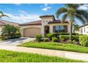 Charming single-story home with a red tile roof, lush landscaping, and a two-car garage at 23493 Copperleaf Dr, Venice, FL 34293