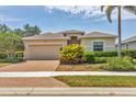 Inviting single-story home with a well-manicured lawn and a paver driveway leading to the attached two-car garage at 24849 Pennington Ter, Venice, FL 34293