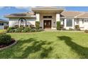 Charming home showcases lush landscaping, a well-maintained lawn, and double door entry at 314 Oakwood Cir, Englewood, FL 34223