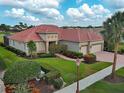 Expansive home with a clay tile roof, well-manicured lawn, three-car garage, and beautiful landscaping at 515 Sawgrass Bridge Rd, Venice, FL 34292
