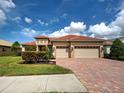 Beautiful home with a brick driveway, three-car garage, clay tile roof, and well-maintained landscaping at 515 Sawgrass Bridge Rd, Venice, FL 34292