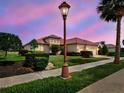 Beautiful home at dusk with a clay tile roof, a three-car garage, and a palm tree next to a sidewalk and street at 515 Sawgrass Bridge Rd, Venice, FL 34292