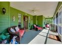 Inviting green porch features cozy seating, ceiling fans, and a charming welcome ambiance at 6293 Taneytown St, North Port, FL 34291
