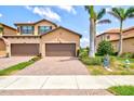 Townhome features a two-car garage with a brick paver driveway and lush landscaping at 10808 Tarflower Dr # 102, Venice, FL 34293
