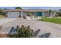 View of the home's exterior features well-maintained landscaping, a turquoise door, and a spacious driveway leading to the garage at 1234 Paradise Way, Venice, FL 34285