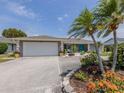 View of the home's exterior showcases beautiful landscaping, a bright turquoise door, and a spacious driveway and garage at 1234 Paradise Way, Venice, FL 34285