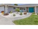 View of the landscaped circular front yard featuring modern xeriscaping and bright turquoise chairs in front of the home at 1234 Paradise Way, Venice, FL 34285