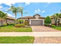 Charming single-story home featuring a well-manicured lawn, brick driveway, and a two-car garage at 13873 Karina St, Venice, FL 34293