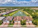 Aerial view of homes shows nice landscaping surrounding a pond with a fountain in a picturesque neighborhood at 20636 Swallowtail Ct, Venice, FL 34293