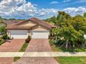 Charming home featuring a paver driveway, two-car garage, and lush landscaping, creating curb appeal at 20636 Swallowtail Ct, Venice, FL 34293