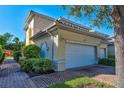 Two-car garage exterior with brick paved driveway and manicured landscaping on a sunny day at 212 Triano Cir # 212, Venice, FL 34292