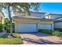 Two-car garage exterior with brick paved driveway and well manicured landscaping in a sunny neighborhood at 212 Triano Cir # 212, Venice, FL 34292