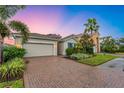 Beautiful single-Gathering home showcasing a brick driveway, a two-car garage, and manicured landscaping at 2150 Snapdragon Ln, Venice, FL 34292