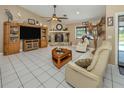 Bright living room with tile flooring, stone fireplace, ceiling fan, and comfortable seating at 2331 Mission Valley Blvd, Nokomis, FL 34275