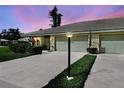 Villa featuring an attached garage, lamp post, and manicured lawn at dusk at 3141 Heron Shores Dr, Venice, FL 34293
