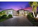 Elegant single-story home featuring a tile roof, paver driveway, attached two-car garage, and well-maintained landscaping at twilight at 329 Myrtle Ave, Nokomis, FL 34275