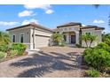 Beautiful home exterior featuring a paver driveway, two-car garage, and tropical landscaping at 329 Myrtle Ave, Nokomis, FL 34275