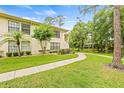Exterior of home featuring well-maintained lawn, mature trees and sidewalk leading to the back at 3382 Mermoor Dr # 3201, Palm Harbor, FL 34685