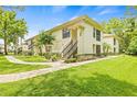 Exterior of a charming two-story home with lush green lawn, garden, and stairs leading to the upper level at 3382 Mermoor Dr # 3201, Palm Harbor, FL 34685