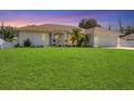 Charming single-story home featuring a manicured lawn and a pristine driveway leading to an attached two-car garage at 381 La Playa Ln, Port Charlotte, FL 33953