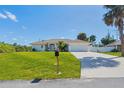 Charming single-story home featuring a manicured lawn and a pristine driveway leading to an attached two-car garage at 381 La Playa Ln, Port Charlotte, FL 33953