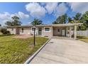 Exterior of a one-story home with a green lawn, carport, and a cozy outdoor seating area at 4192 Tarpon Rd, Venice, FL 34293