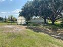 Exterior view of greenhouse, outbuilding, mature trees, and spacious backyard at 5760 Howard Creek Rd, Sarasota, FL 34241