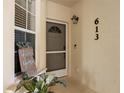 Inviting front entrance with door, Welcome Home sign, a house number of 613, and decorative plant at 600 Gardens Edge Dr # 613, Venice, FL 34285