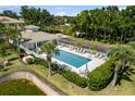 Aerial view of a community pool area with lounge chairs, manicured landscaping, and a nearby clubhouse for residents at 600 Gardens Edge Dr # 613, Venice, FL 34285