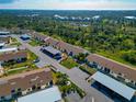 Aerial view of condo community surrounded by lush landscaping, woods, and a pond; close to area beaches at 6796 Gasparilla Pines Blvd # 18, Englewood, FL 34224