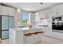 Bright kitchen boasts a center island, white cabinets, pendant lighting, and stainless steel appliances at 10121 Beachwalk Dr, Englewood, FL 34223