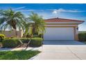 Inviting home featuring lush landscaping, mature palm trees, and an attached two-car garage at 102 Mestre Pl, North Venice, FL 34275