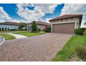 Home exterior showing the brick-paved driveway, well-maintained landscaping and a two-car garage at 10410 Inglenook Ter, Palmetto, FL 34221