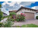 A detailed exterior image showing the brick paved walkway and two car garage with beautiful landscaping at 10410 Inglenook Ter, Palmetto, FL 34221