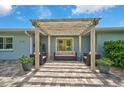 A cozy patio features comfortable seating beneath a pergola with string lights and leads to vibrant green doors at 1099 Nokomis S Ave, Venice, FL 34285