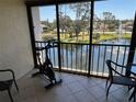 Enclosed balcony features an exercise bike with serene views of the community lake and fountain at 1154 Bird Bay Way # 303, Venice, FL 34285