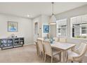 Bright dining room with tile floors, modern pendant lighting, and a stylish blue and grey sideboard cabinet at 12538 Somatic Ct, Venice, FL 34293