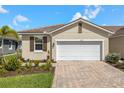 Charming single-story home featuring a well-manicured lawn and a two-car garage with brick paved drive at 12538 Somatic Ct, Venice, FL 34293