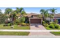 Charming home features a two-car garage, tile roof, lush landscaping, and a brick paver driveway at 13829 Alafaya St, Venice, FL 34293
