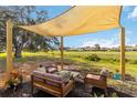 Backyard patio with comfortable seating beneath a modern shade structure and a view of the community green space at 1439 Strada D Argento, Venice, FL 34292