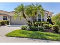Charming home with a well-manicured lawn, palm trees, and an attached garage at 165 Tiziano Way, North Venice, FL 34275