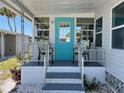 Welcoming front porch with a blue door, seating, and stylish decor enhancing the home's curb appeal at 202 Mantua Dr, Venice, FL 34285