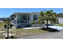 Inviting single-story home featuring a charming porch, well-maintained landscaping, and a palm tree at 202 Mantua Dr, Venice, FL 34285